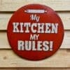 Tavla skylt "My kitchen, My rules" Vintage skyltar i plåt. Skylt för kök, utekök, grillhörna Dekorera din favoritplats med skyltar och metalltavlor i rustik vintage design som bjuder in till ett skratt eller två ;) Rund plåtskylt med texten "My kitchen, my rules".  Snygg skylt som fördelar brödkaveln till ägaren av köket  (extra rätt om ägarinnan råkar heta My...) - rättvisan när den är som bäst. Denna skylt är "embossed" alltså  präglad, utbankad med förhöjningar som ger ett snyggt djup i bilden.  Tavlor i metall och plåtskyltar? BBQmonster har en häftig samling tavlor och skyltar i metall som kan vara den perfekta presenten eller tillbehöret till presenten som gör pricken över i:et, eller "the prick over the eye" som man säger i Amerikat... Metalltavlor för grill och BBQ är efterfrågade dekorer till utekök, mancaves och grillhörnor och med BBQmonsters uppsättning är chansen god att du hittar en skylt som passar just dig eller den person du skall köpa presenten till. Ett presenttips kan vara att om du köper låt säga ett paket spanska ginglas att då komplettera med en skylt som förstärker budskapet. Samma sak kan appliceras Ölglas, Kamados osv. Livsnjutare, Foodies och grillare är ofta glada för både god mat och god dryck. Därför kretsar många av dessa vintage skyltar och metalltavlor på tema Mat, såsom recepttavlor (för exempelvis Pulled pork, Revben / Ribs och Brisket). Eller Dryck (whisky, bourbon, beer, öl, IPA, Cider, Stout och inte minst modedrycken GIN). Tavlan hänger du enkelt upp på en spik eller skruv, i snöret som medföljer. Du kan även använda dubbelhäftande tejp om det passar bättre mot underlaget. My kitchen, my rules - en plåtskylt, rund modell 30cm i diameter, med text och bild präglat ur plåten. Du hittar alla tavlor och skyltar under kategorin Tavlor metall (www.bbqmonster.se/produkt-kategori/tavlor/) Tavla till hemmakocken