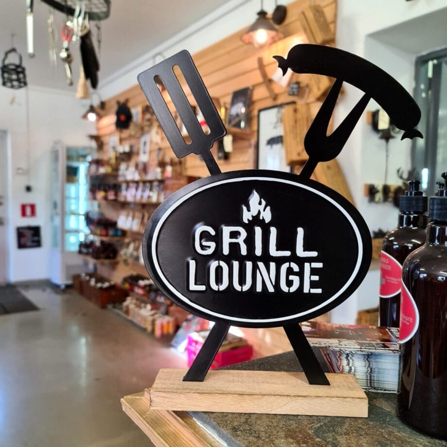 Bordsdekor BBQ / Grill-lounge snyggt i köket eller uteköket av trä och metall 30cm höga Detta är en bordsdekor av trä och metall. Bordsdekorationen finns i två olika versioner som ger följande budskap: Grill Lounge BBQ Lounge  Passar perfekt i uteköket och grillhörnan. Mysigt i stugan och grillhörnan inredning för en "Lodge lifestyle" och "Cottage lifestyle" BBQmonster har lanserat ett utvalt koncept av prylar som ryms inom begreppen BBQlifestyle, Lodge lifestyle och Cottage Lifestyle, en växande trend är nämligen att vi söker oss mot en inredning som skall ge oss lugn och gemyt. För många är sannolikt den ultimata målbilden en spartanskt inredd stuga, gärna med träväggar, öppen spis och en lurvig fäll på golvet. I dessa två koncept skall BBQmonster försöka hitta guldkornen (eller silver eller trä...) som symboliserar och skapar känslan av mysfaktor hög. Butiken i Ödåkra är i sig själv inredd med liggande träpanel och inredning som skall skapa en skön känsla, Det är utifrån kunders frågor kring inredning som BBQmonster fick idéen att utöka med dessa Lodge Lifestyle och Cottage Lifestyle. Planen är inte att göra om BBQmonster till en inredningsbutik, utan fokus kommer fortsatt vara på GRILL och BBQ - men då livsnjuteri vid grillen är starkt närbesläktat med livsnjuteriet som sker under en weekend i stugan, i fjällen eller kanske i ditt hem som du format utefter att få känslan av en timmerstuga, jaktstuga eller någon annan målbild som du ser för ditt inre.