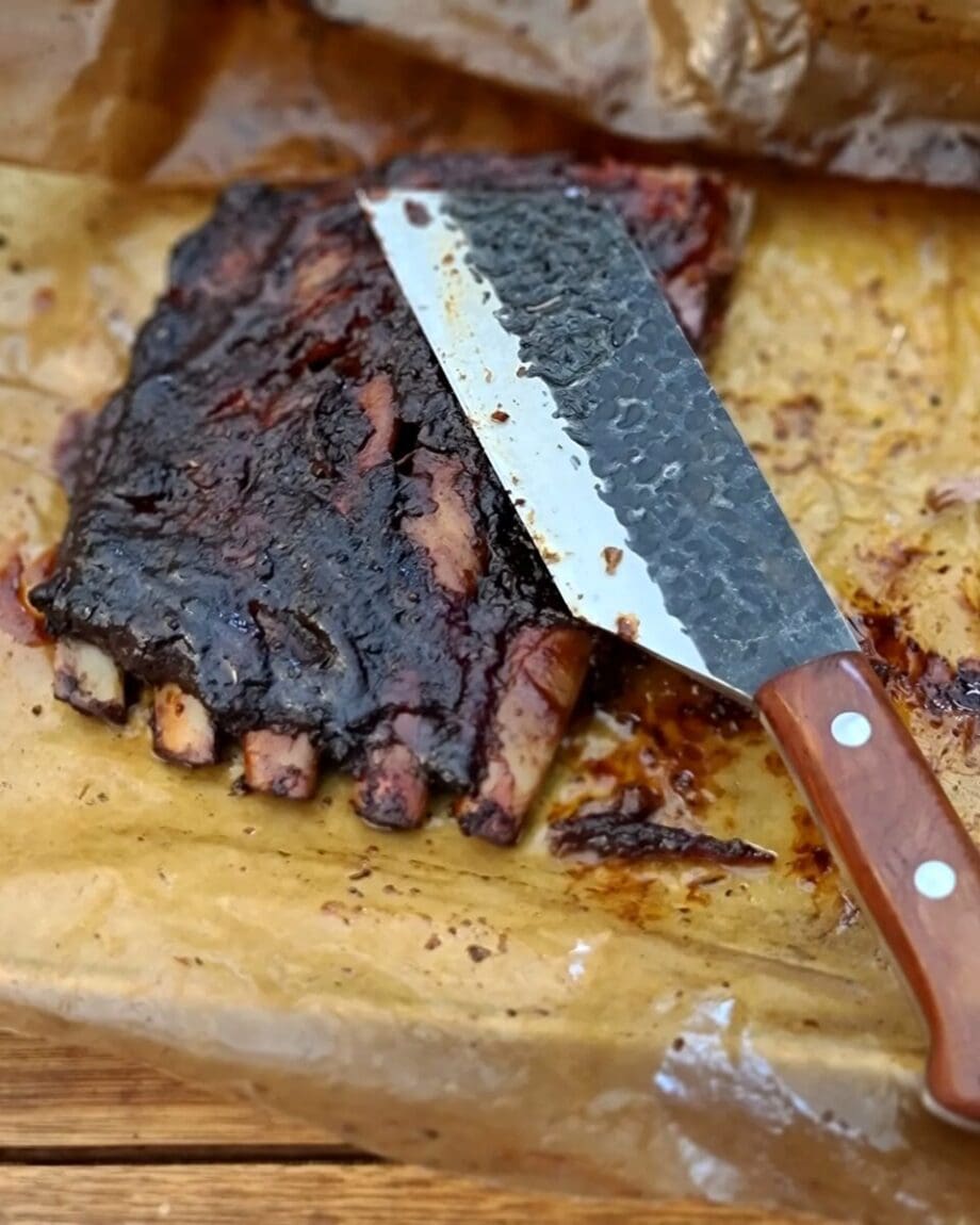 BBQ-kniv Kockkniv BBQmonster - robust kniv/cleaver med slida i läder. 5mm grov rygg och en vikt på 400 gram En bbq-kniv för BBQ och Grillning: BBQmonster BBQ-kniv / cleaver är kniven som är en kombination av en rejäl kockkniv och en Cleaver / köttyxa, och med denna i din hand är inte en kotlettrad eller ett revbensspjäll säkert någonstans. Bladet är EXTREMT stabilt och viker inte även vid hårdare tag. Ryggen är hela 5mm tjockt och större delen av bladet har en härlig hammrad yta som kniven rejält "intstagramvänlig" och photogenique. Denna BBQkniv kommer en slida av läder vilket gör att du kan bära den i din livrem eller i ditt förkläde. Skaftet är av polerat och lackat hårdträ och detta omsluter det genomgående knivbladet avslutning. Skaftet ger ett bra grepp och är enkelt att rengöra. Handtaget passar både höger- och vänsterhänta. Kolstål med blandning X50CrMoV15 Hårdhet 56° HRC vilket är ett relativt mjukt stål - något som gör att du själv enkelt kan hålla din kniv vass. Total längd: 29 cm Längd på bladet: 18 cm Längd på skaftet: 11 cm