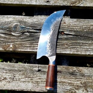 Sabelformad Cimeterkniv "Anchor" 31cm - hamrat stål, fina detaljer och galet vass - säljs för det tredubbla på andra sidor! Söker du en serie av välarbetade och lättskötta kockknivar? Ta en kik på BBQmonsters  "Anchor-series". Introduktionspris - passa på! Denna modell av kökskniv är av typen sabelformad eller cimeterkniv som typen av kniv även kallas. Formen av knivbladet gör den lämplig till att med en "gungande" rörelse hacka kött eller grönsaker till mindre bitar. Givetvis går det utmärkt att skära kött i skivor etc. men bladets form kommer ännu bättre till sin rätt när det får gunga. Bladet är stabilt, lättskött och bladet har en härlig hammrad yta som kniven rejält "intstagramvänlig" och photogenique. Mässingsringar förbinder eggen med handtaget som är av polerat och lackat ädelträ. Skaftet ger ett bra grepp och är enkelt att rengöra. Handtaget passar både höger- och vänsterhänta. Handtaget avslutas med en fördjupad urfräst symbol föreställande ett ankare (anchor). Kolstål med blandning X50CrMoV15 Hårdhet 56° HRC vilket är ett relativt mjukt stål - något som gör att du själv enkelt kan hålla din kniv vass. Total längd: 31 cm Längd på bladet: 20 cm Längd på skaftet: 12 cm